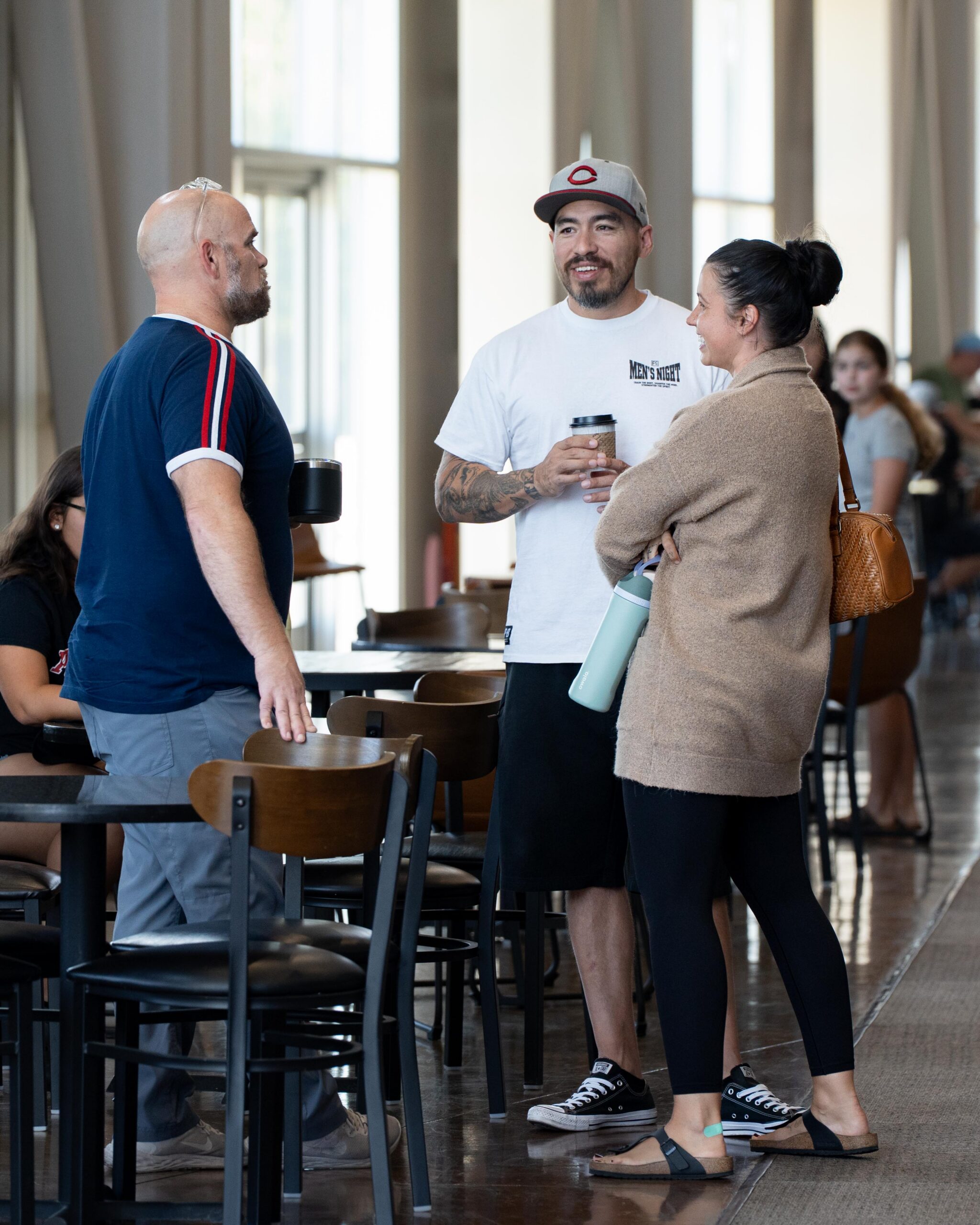 Three people talking together over coffee