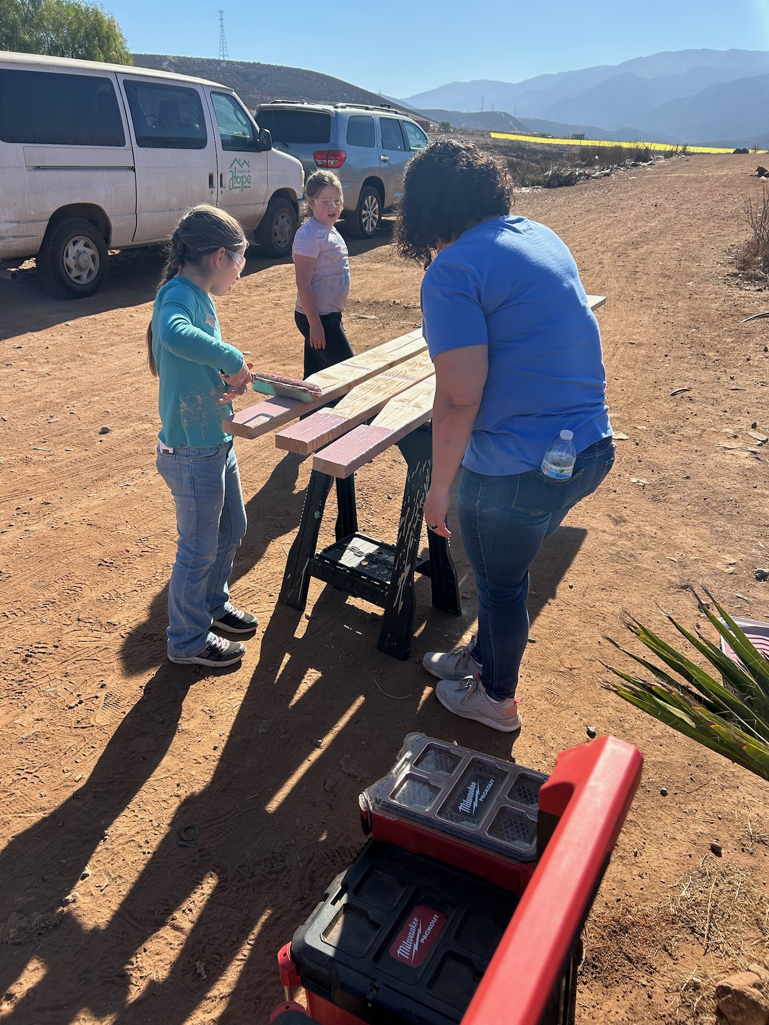 Homes of Hope build trip Volunteers and children building a wooden table together on a missions trip