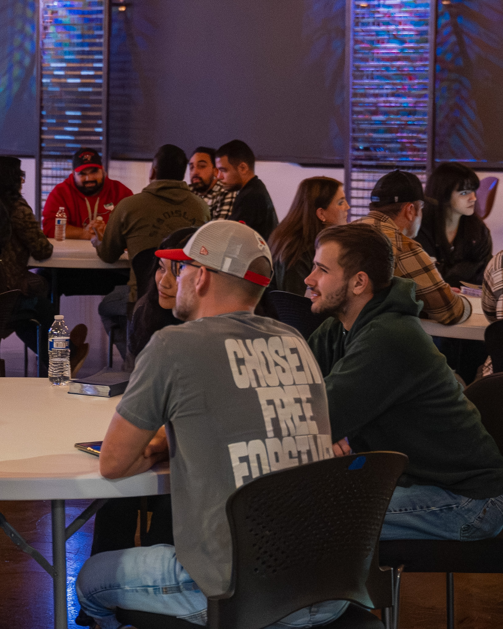 Young adults sitting and talking together at tables during a Cove Young Adults gathering