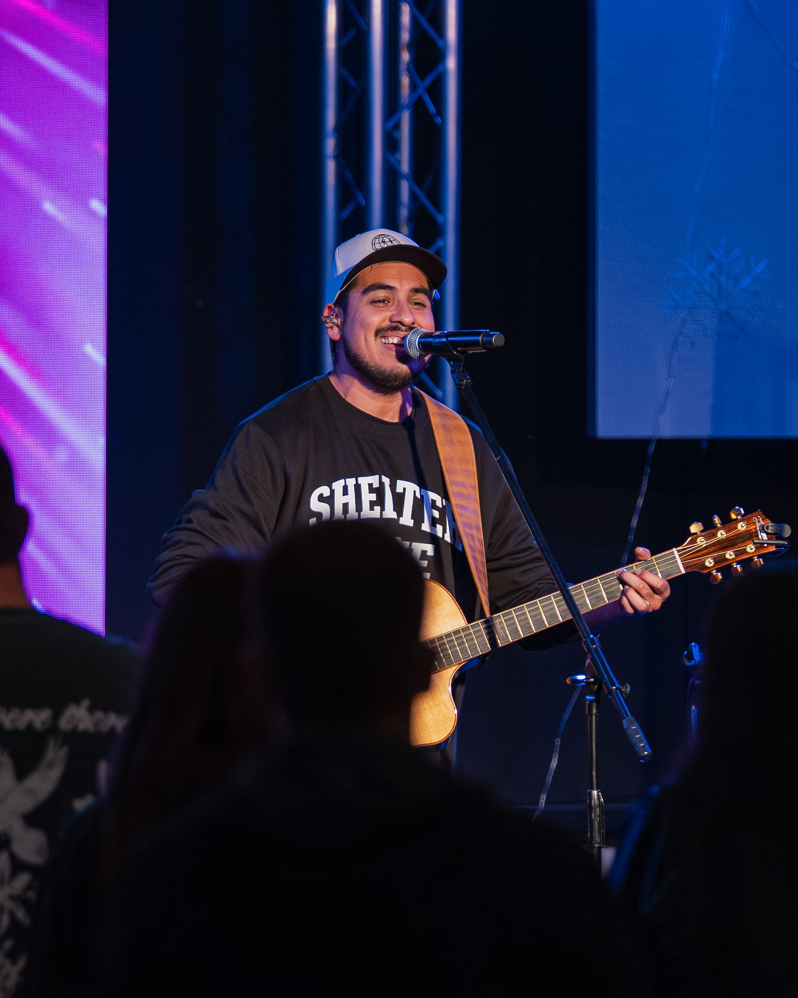 A young man singing and playing guitar on stage during a Young Adults worship night