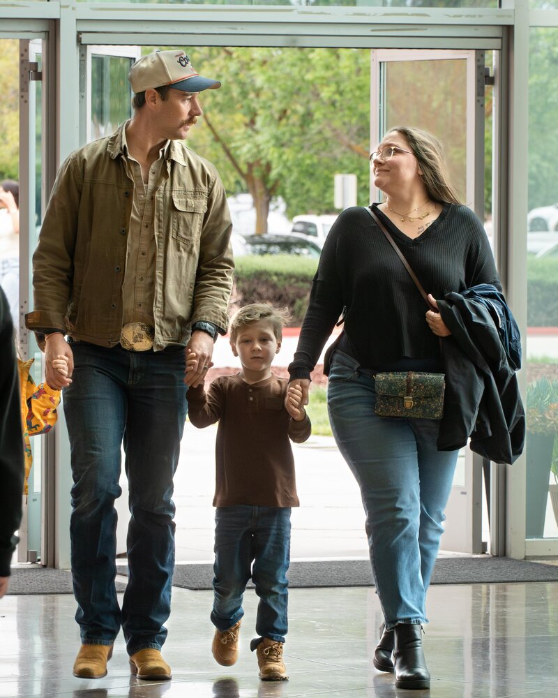 A family holding hands and walking together through the church entrance