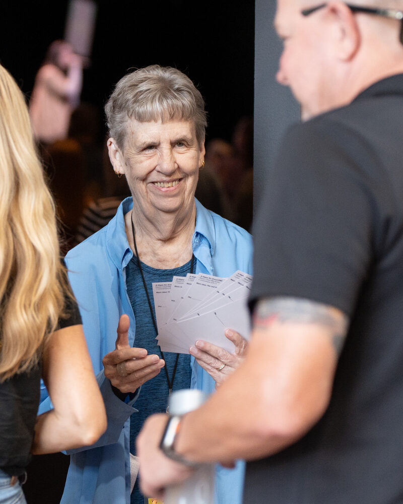 A woman talking with a volunteer while holding papers at a Cove Seniors event