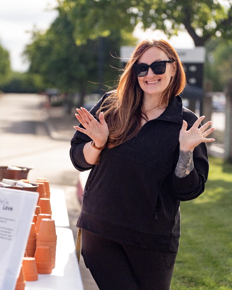 A woman smiling and clapping outdoors at a Cove Women event