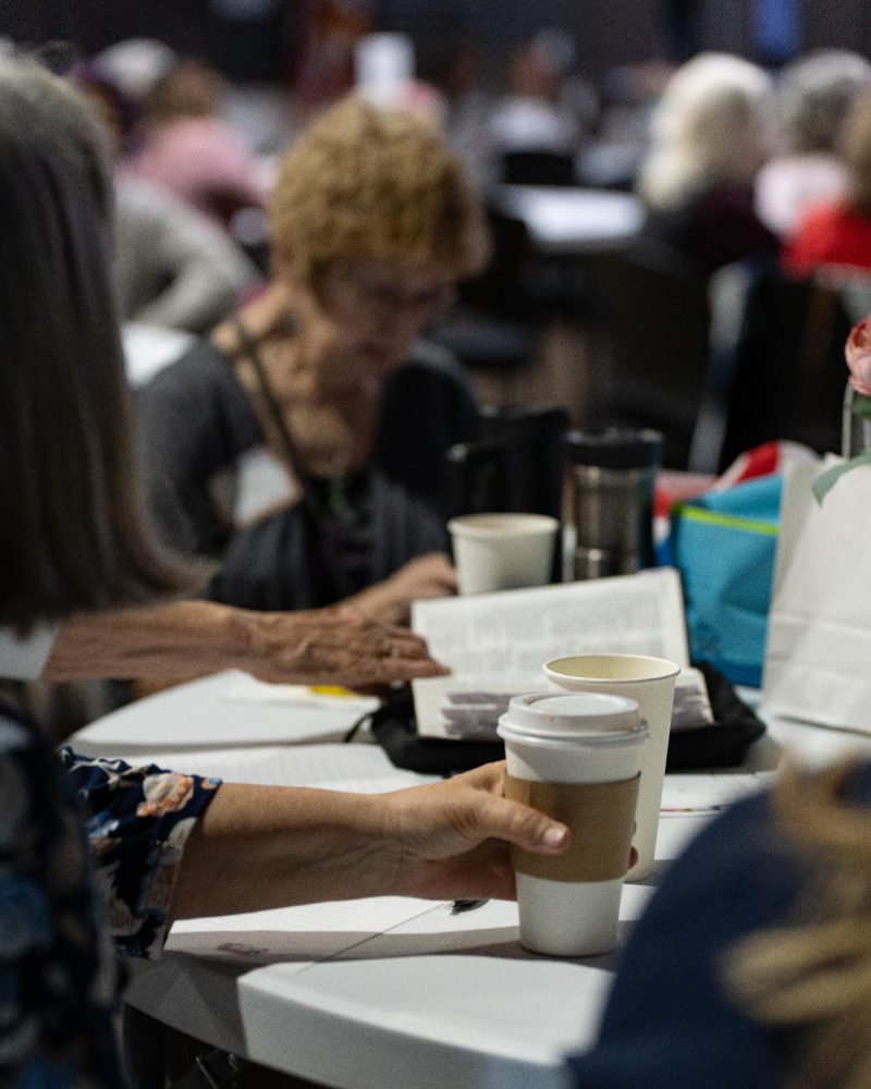 Women writing and journaling together at tables during a Cove Women gathering
