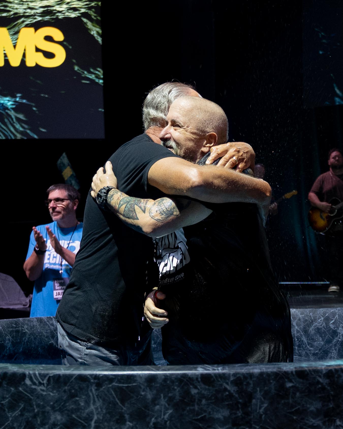 Two men embracing in the baptism tub in celebration after a baptism at Shelter Cove Community Church