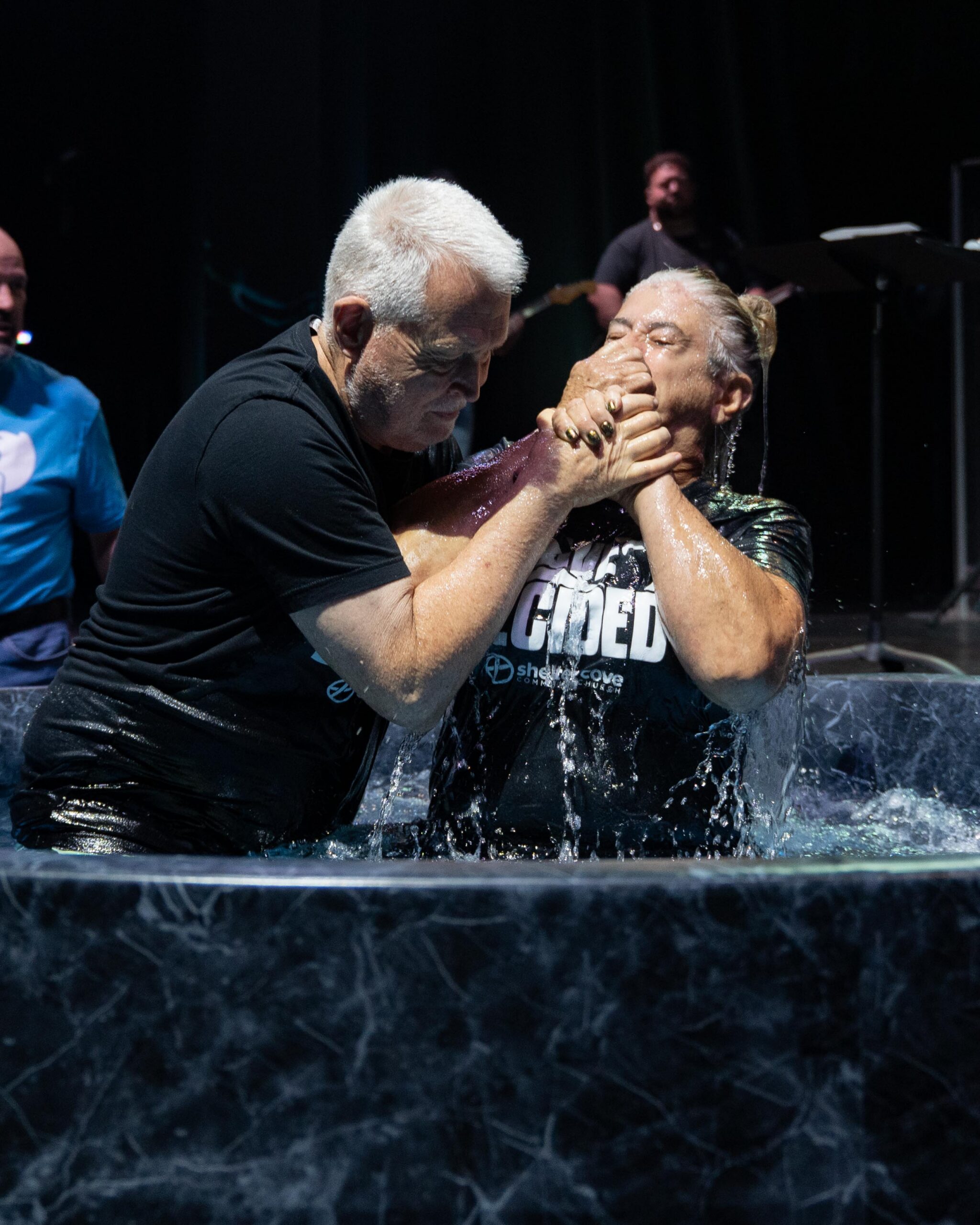 An older pastor and a woman wearing an I Have Decided shirt smiling together after her baptism