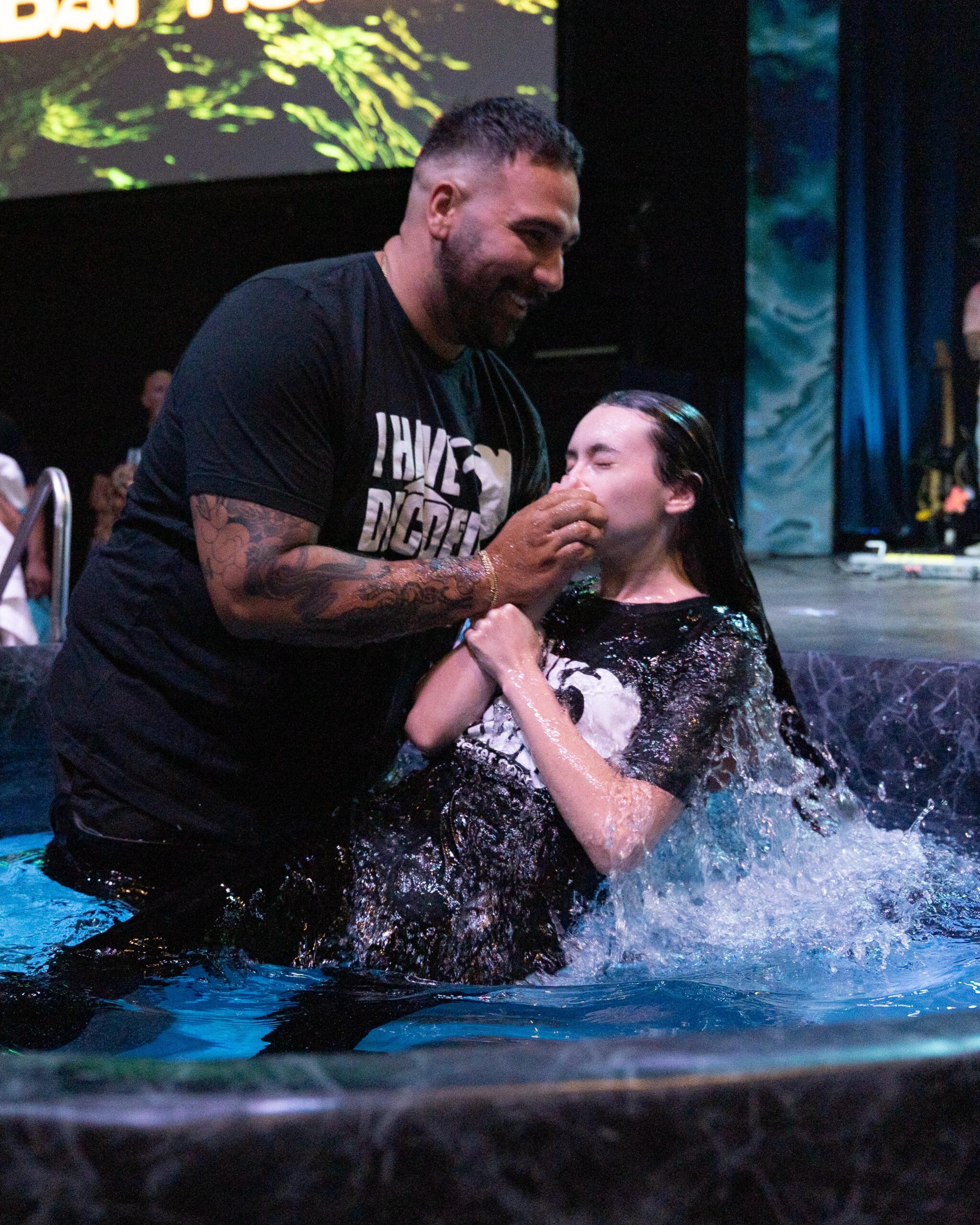 A pastor wearing an I Have Decided shirt baptizing a young woman at Shelter Cove Community Church