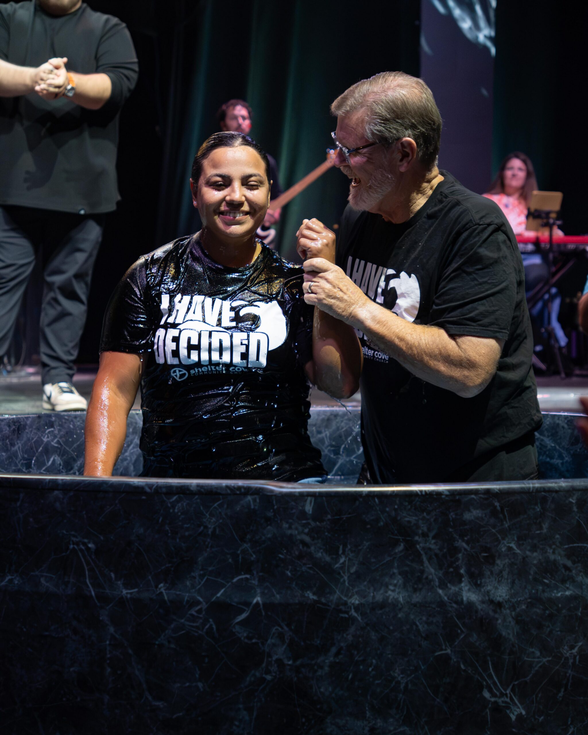 A woman smiling with a pastor after being baptized, wearing an I Have Decided shirt