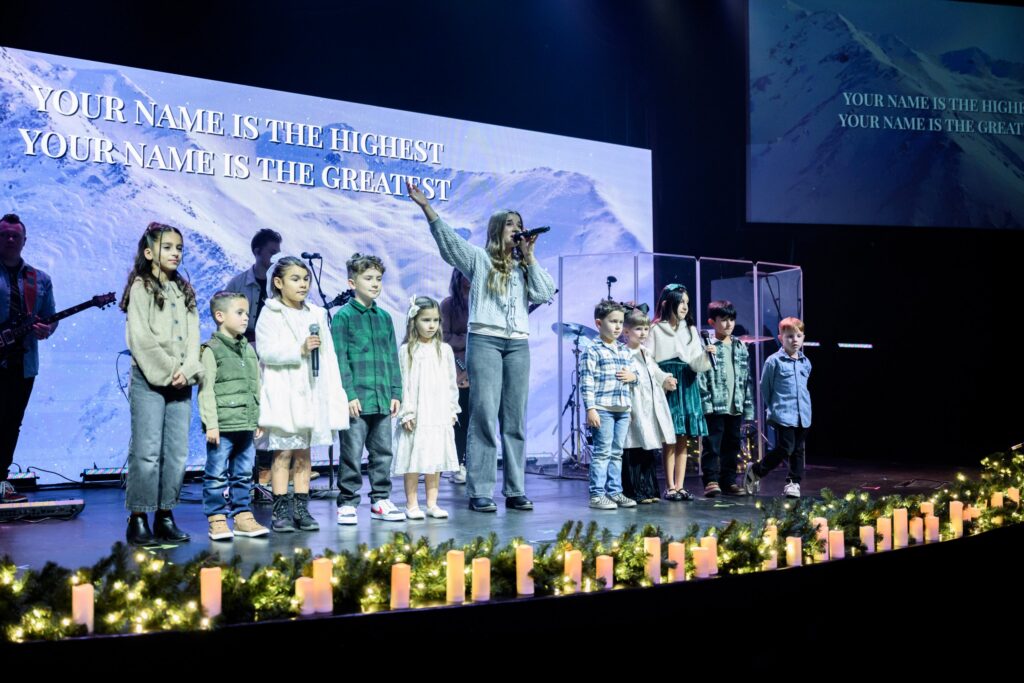 Kids singing on stage with the worship team at a Christmas service
