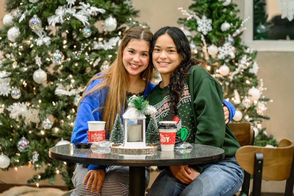 Two friends sharing hot cocoa by the Christmas tree